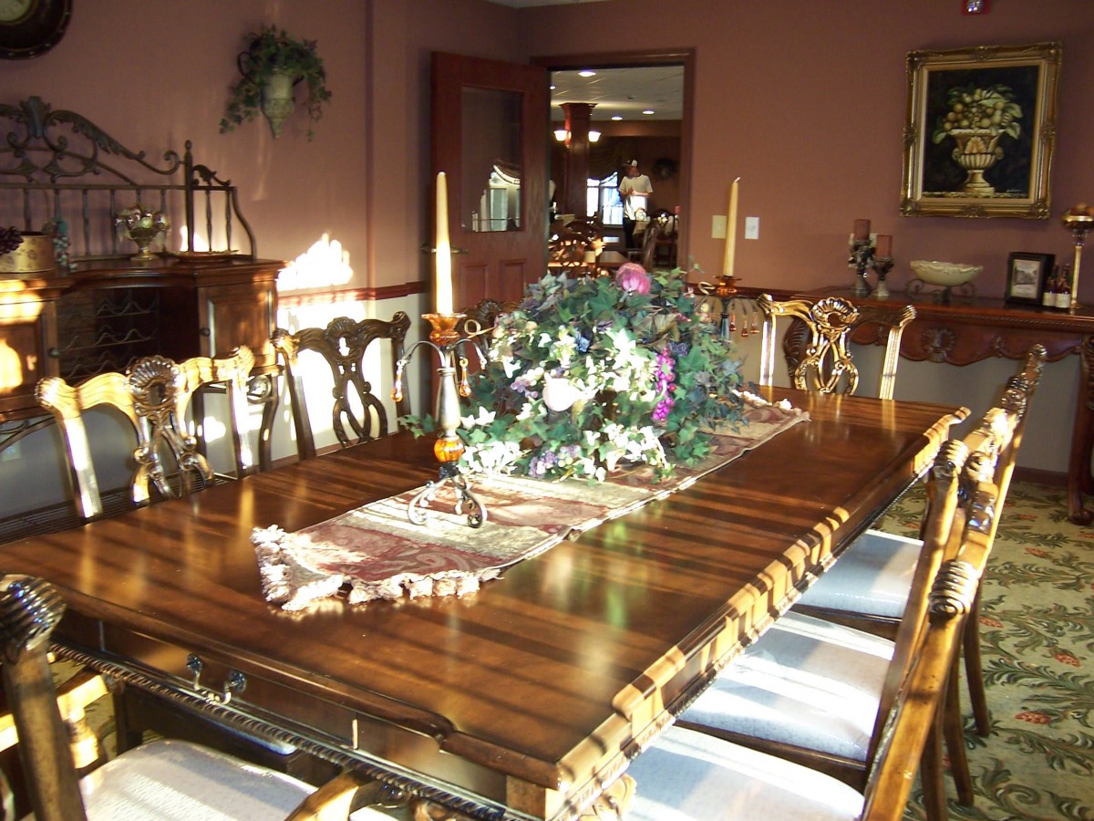 A well-decorated dining room with a large wooden table and elegant chairs, featuring a floral centerpiece.