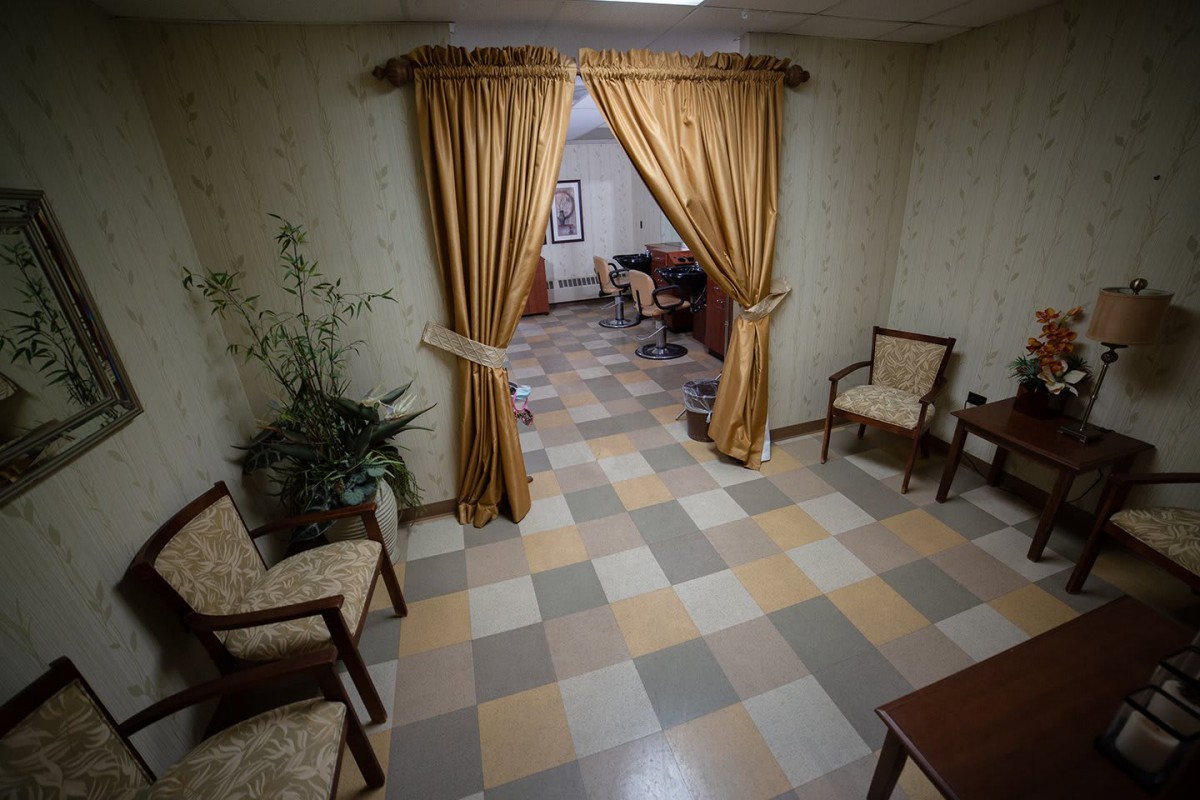 A cozy waiting room with tiled flooring and curtains separating an adjacent area.