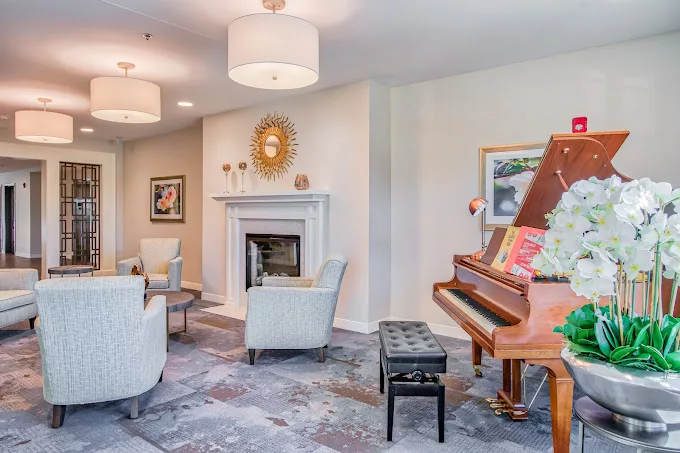 A cozy living room featuring a piano, comfortable seating, and a fireplace.