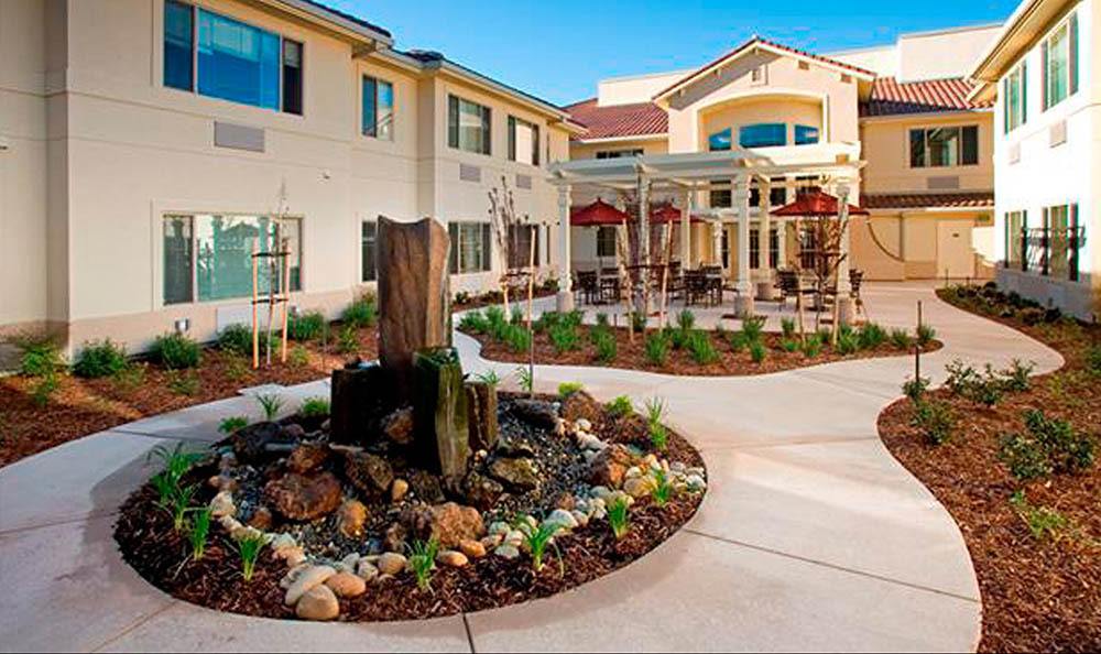 A beautifully landscaped courtyard with a fountain in front of a modern building.