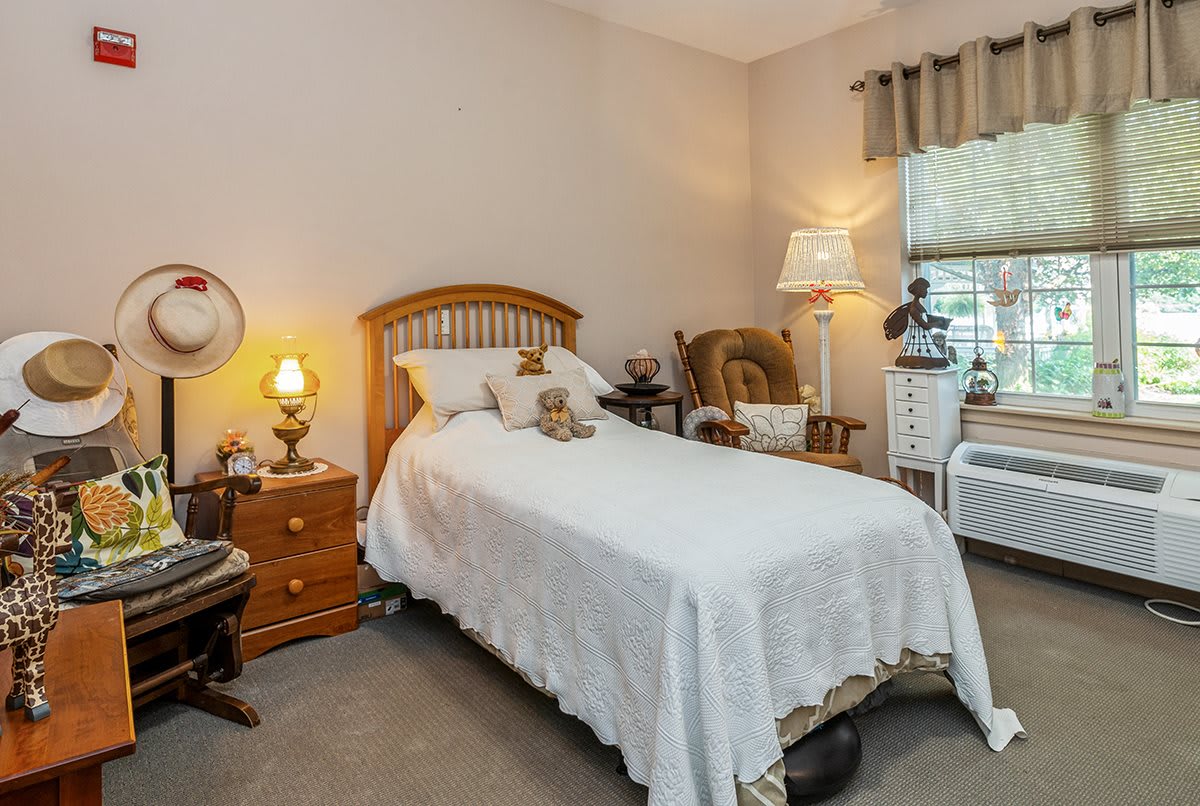A cozy bedroom with vintage decor featuring a single bed, nightstand, and armchair.