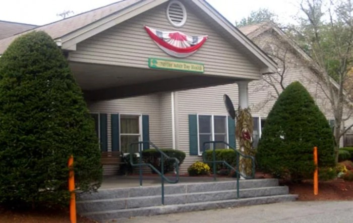 A decorated building entrance with stairs and greenery on either side.