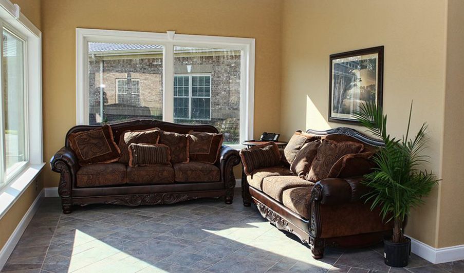 A cozy living room featuring a brown couch and loveseat set by a large window allowing natural light to fill the space.