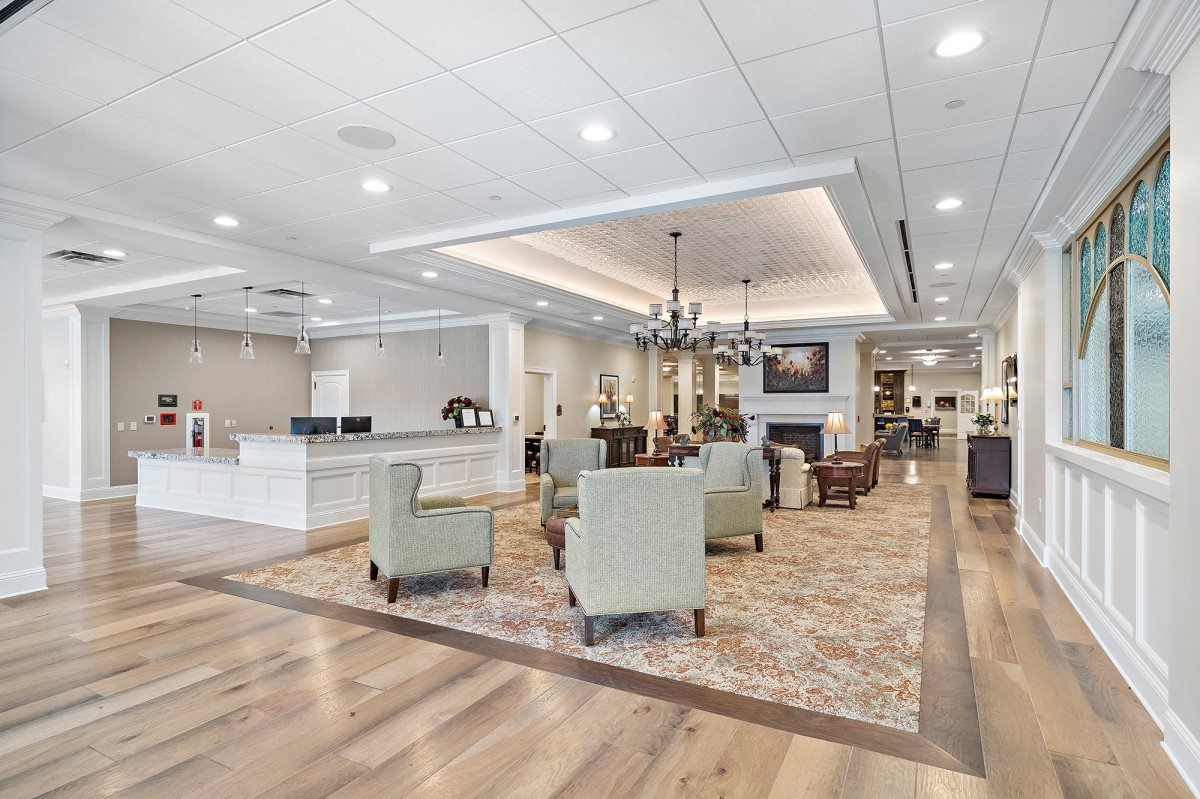 A modern lobby interior with a seating area, chandelier, and reception desk.