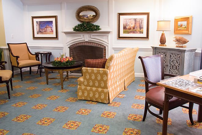 A cozy living room with a patterned sofa, elegant fireplace, and decorative artwork on the walls.