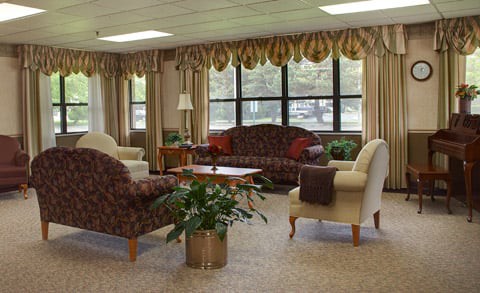 A cozy living room with elegant furniture, large windows, and potted plants.