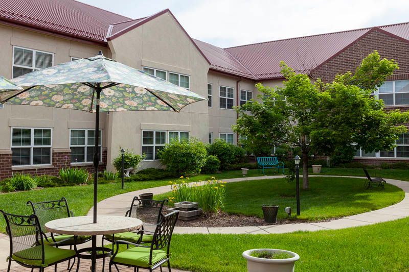 A well-maintained courtyard with patio furniture and lush greenery in front of a residential building.