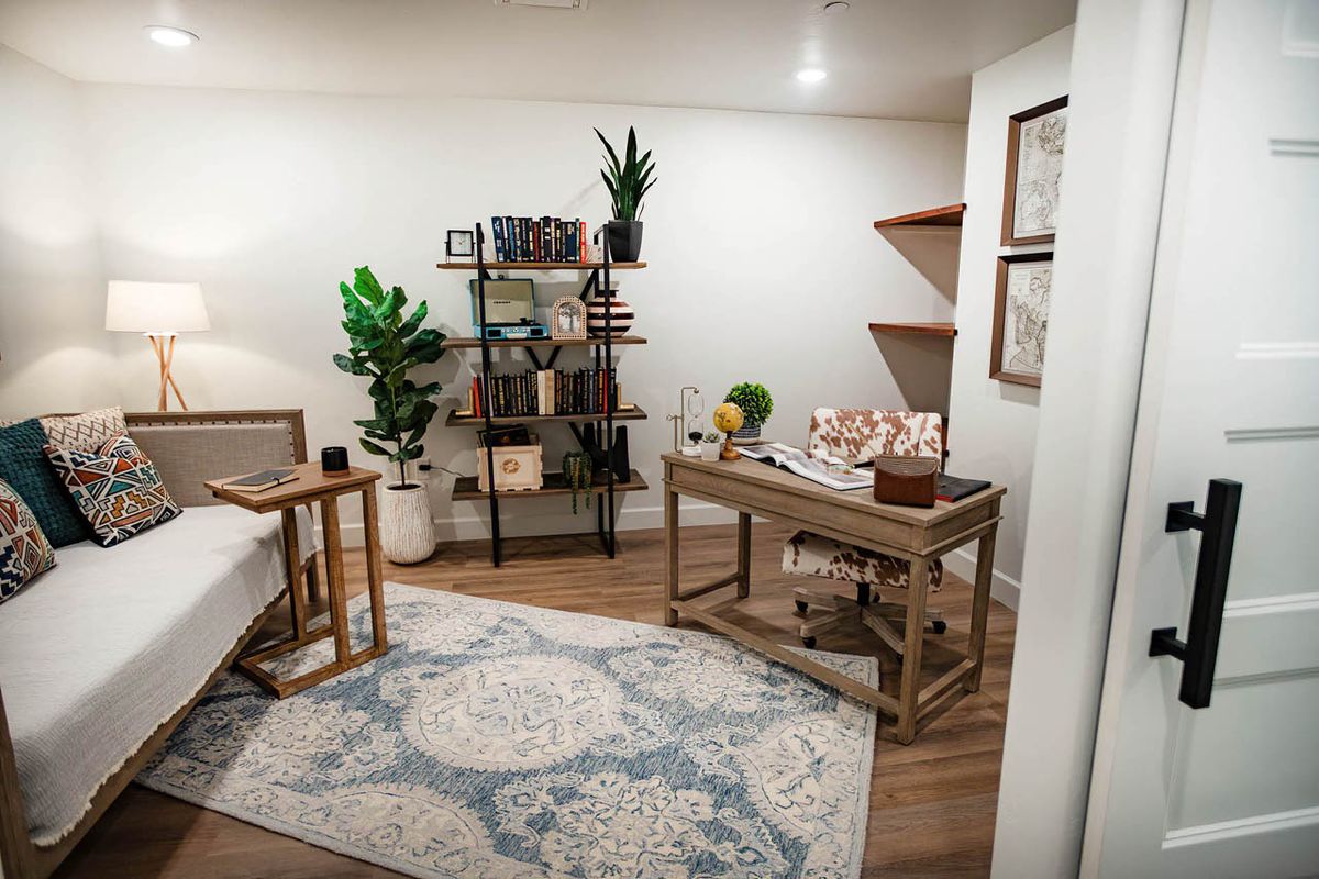A cozy and modern home office with a wooden desk, bookshelf, and decorative plants.