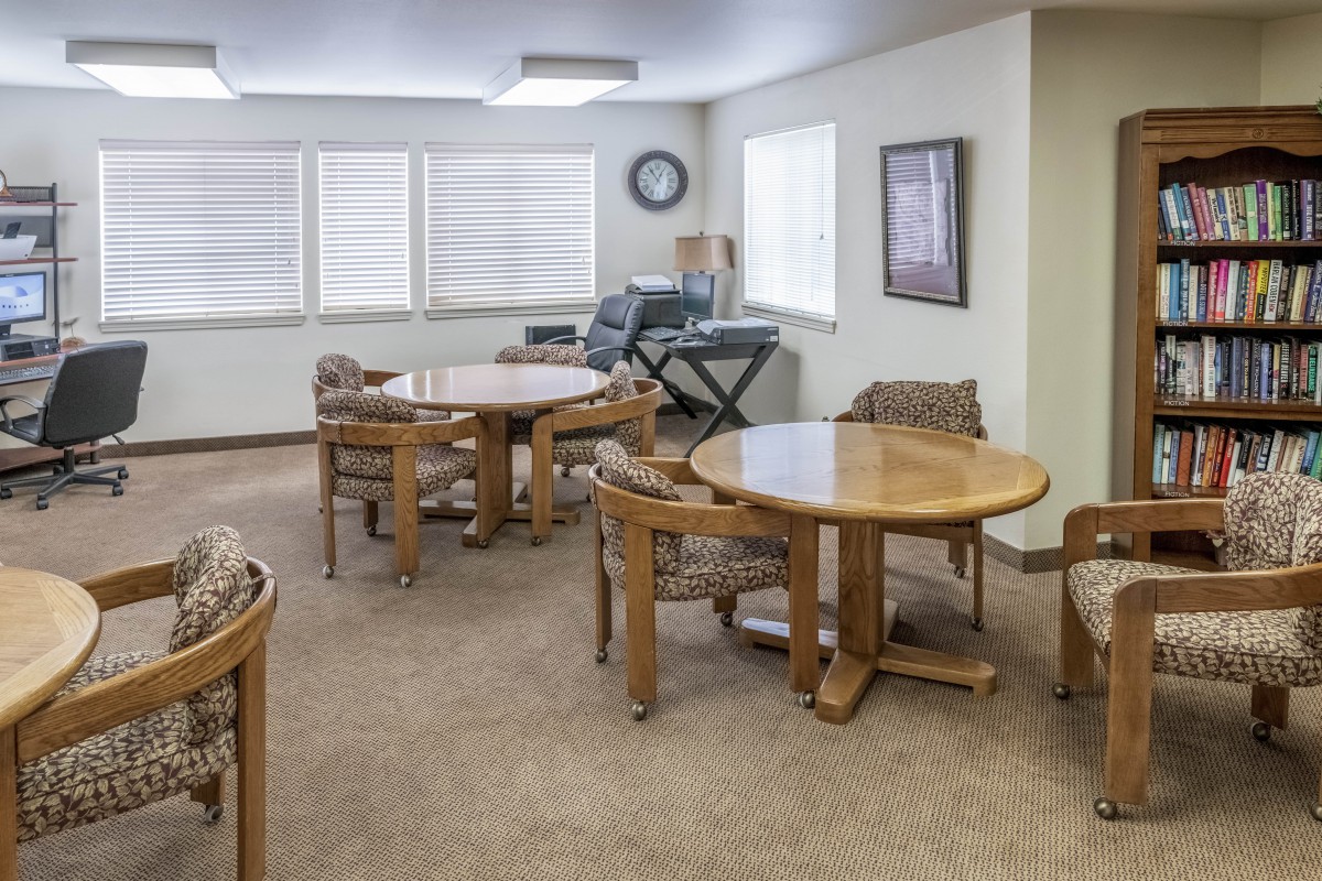 A well-lit meeting room with round tables and chairs, featuring a piano keyboard in the corner.