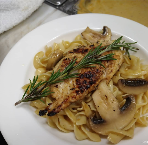 A delicious plate of fettuccine pasta topped with grilled chicken, sauted mushrooms, and fresh herbs.