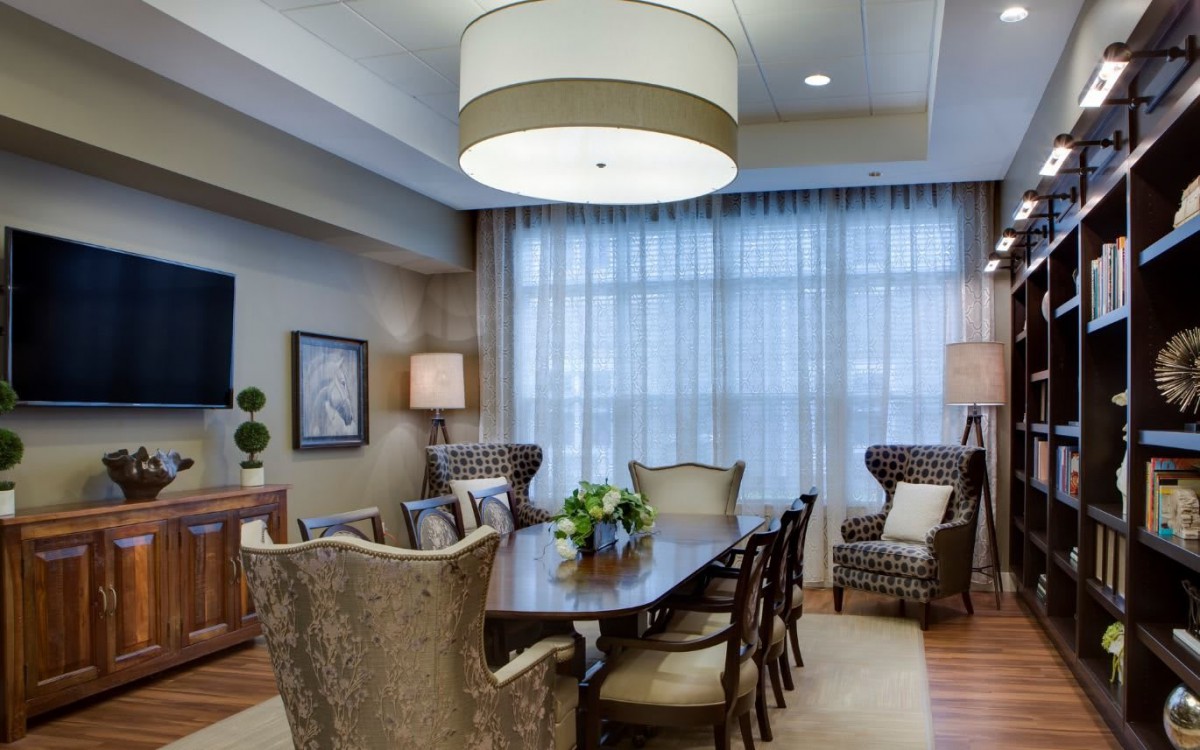 A well-appointed dining room featuring a large table surrounded by chairs, elegant lighting, and airy curtains.