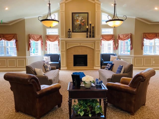 A cozy living room with comfortable seating, a central fireplace, and elegant chandeliers.