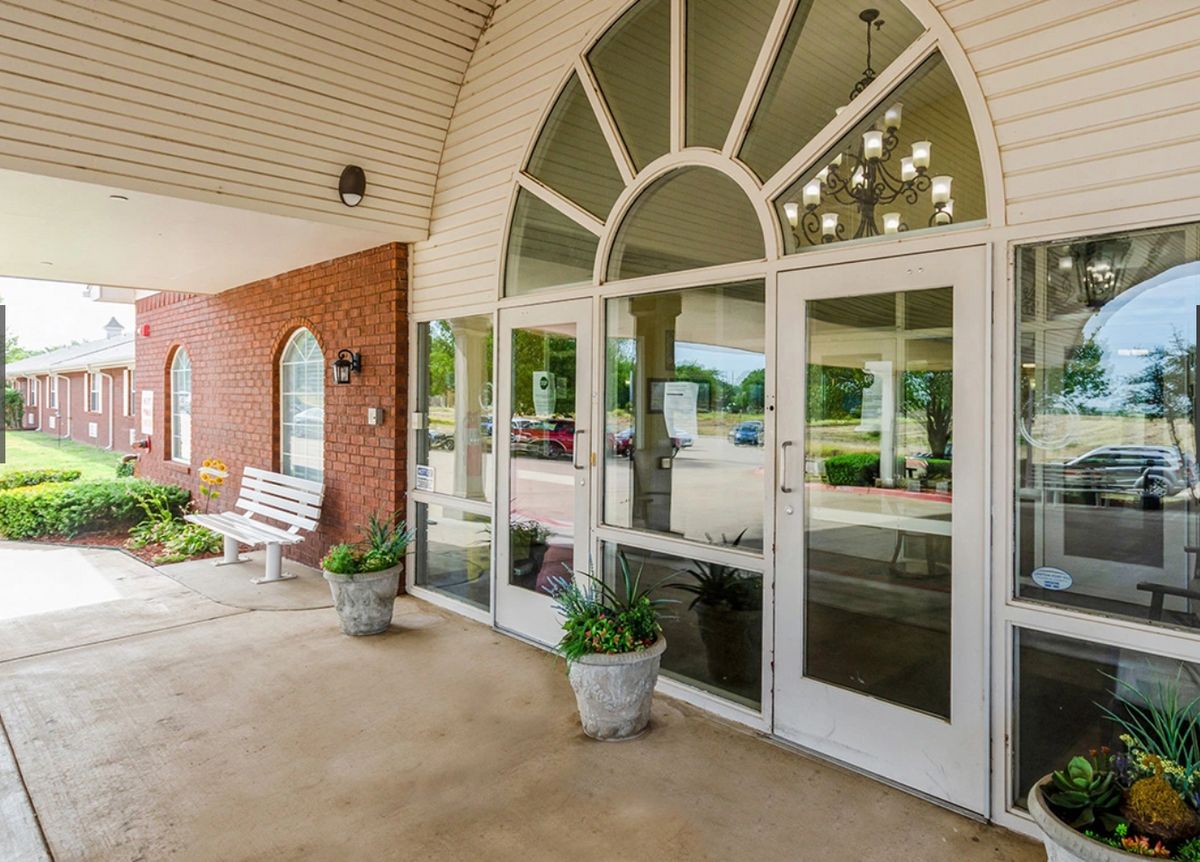 Entrance of a building with glass doors and potted plants.