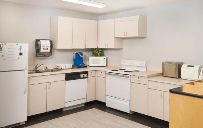A modern kitchen featuring light-colored cabinets, a stove, microwave, dishwasher, and ample countertop space.