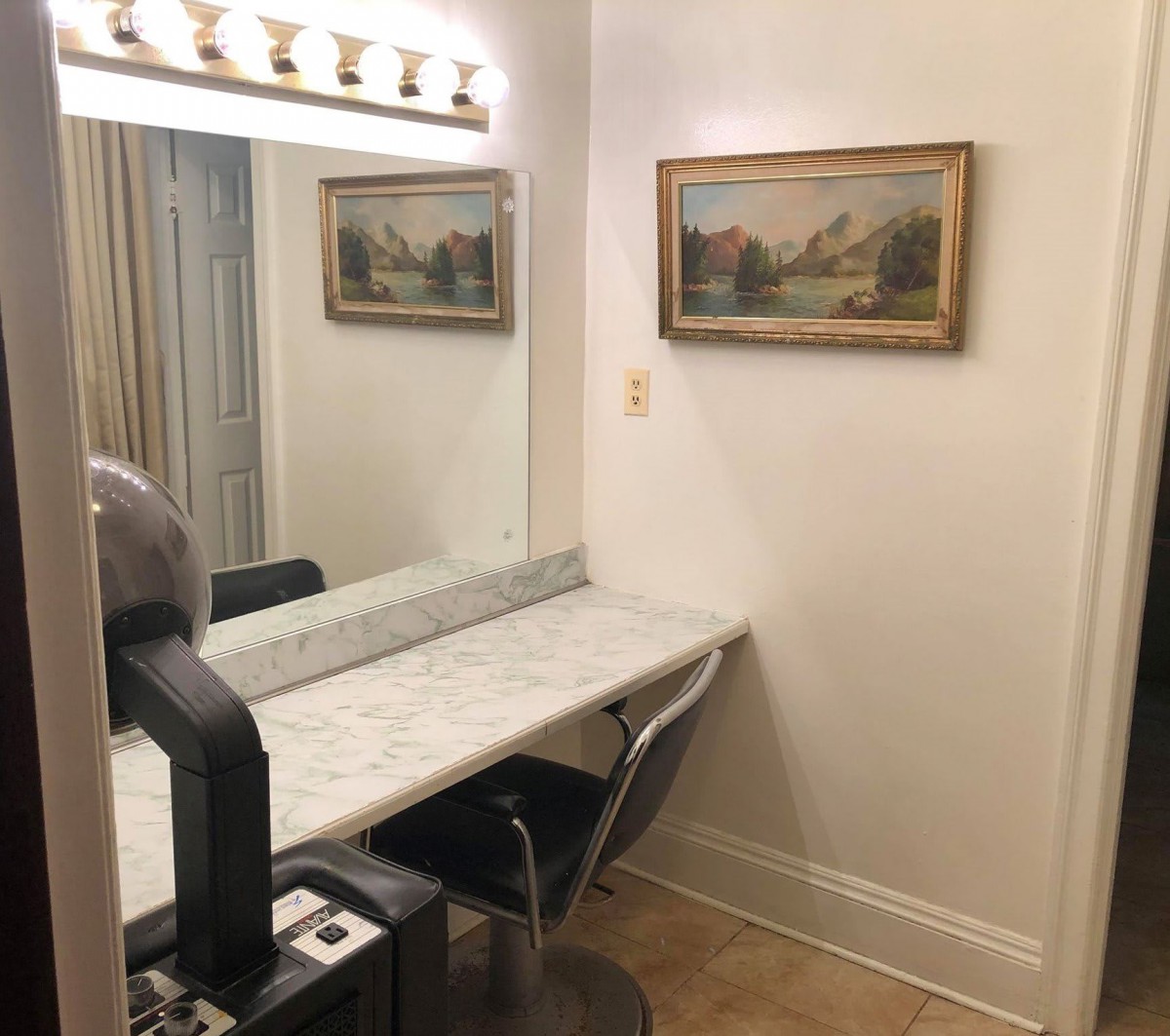 A well-lit vanity table with a mirror and wall art in a cozy corner.