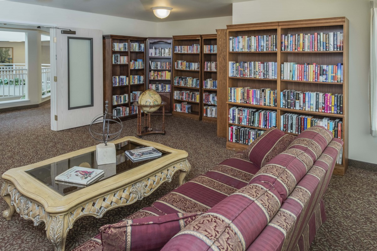 A cozy library reading area with bookshelves, a sofa, and a coffee table.