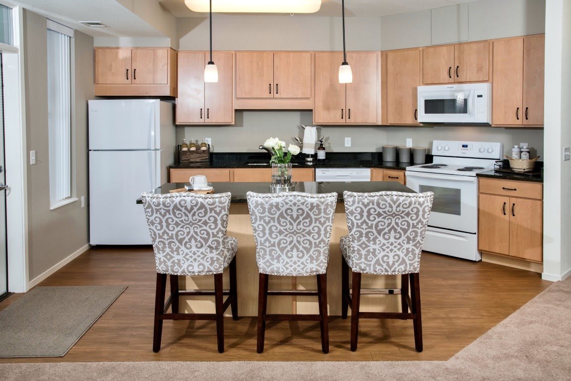 A modern kitchen with a central island featuring three patterned bar stools and pendant lighting.