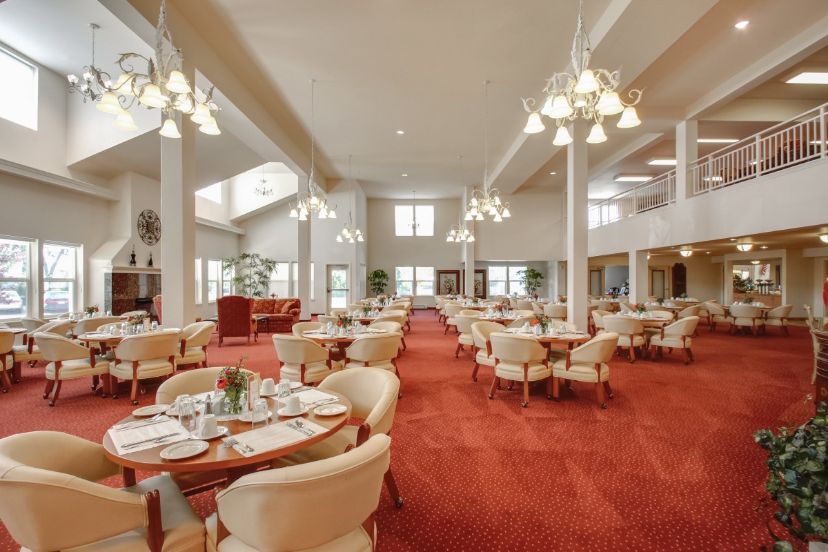 An elegant dining area with neatly arranged tables and chairs, adorned with chandeliers.