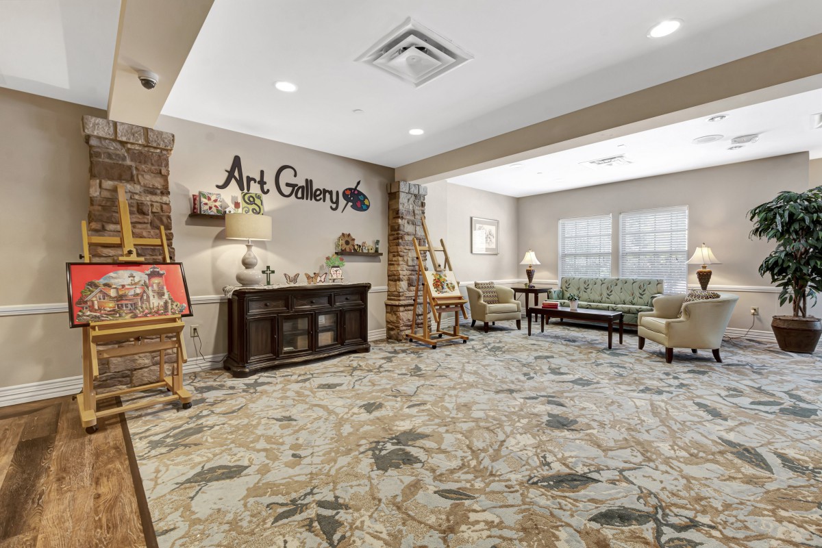 A cozy art gallery interior with paintings on easels and comfortable seating.