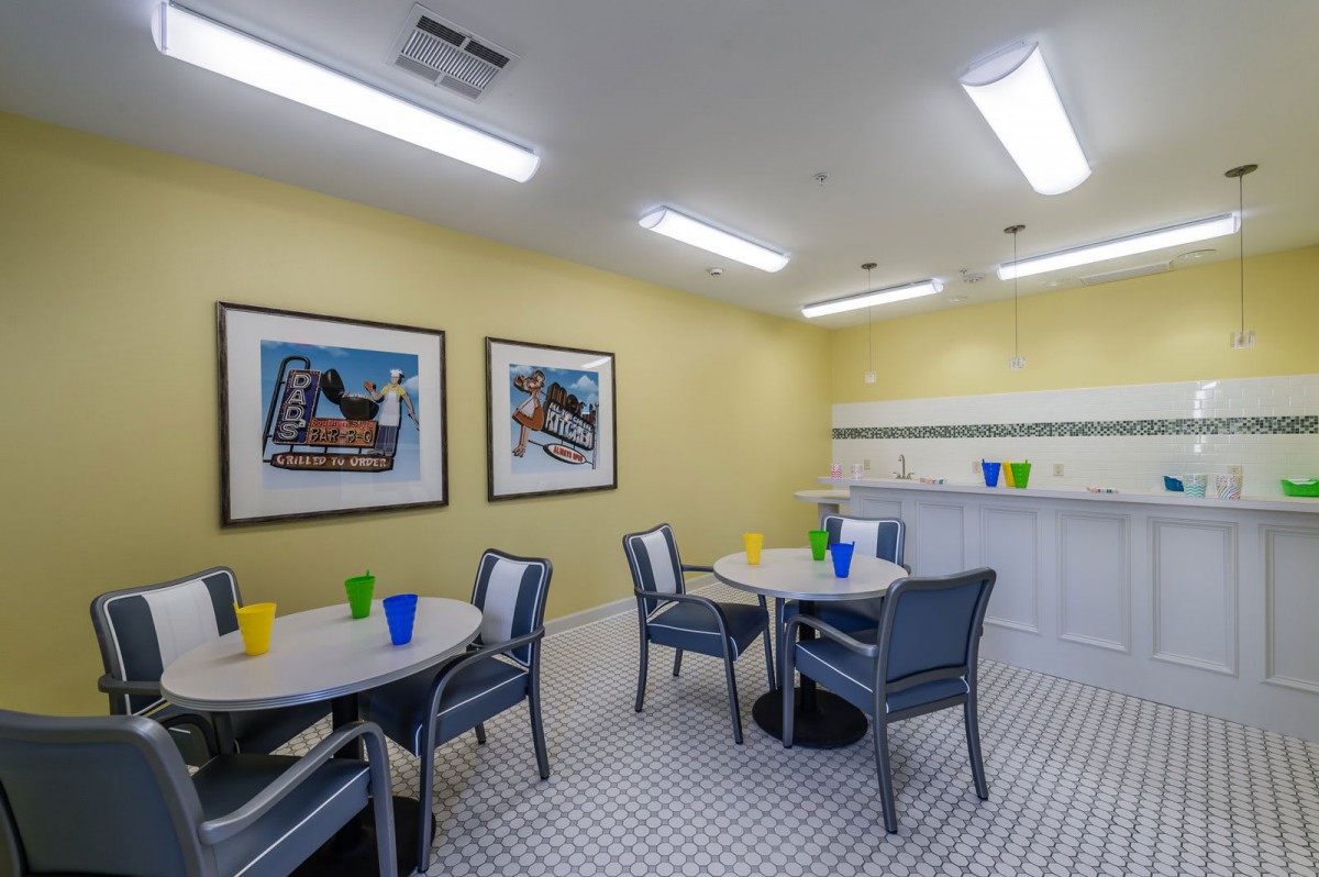 A brightly lit indoor dining area with tables and chairs, decorated with colorful cups and artwork on the walls.