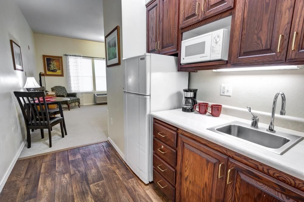 A cozy apartment kitchen featuring wooden cabinets, a microwave, refrigerator, and a coffee maker on the countertop.