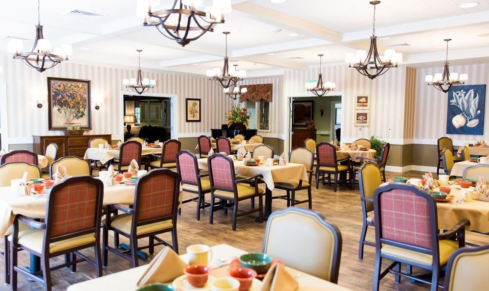 An elegant dining area with neatly arranged tables and chairs, featuring chandeliers and stylish decor.