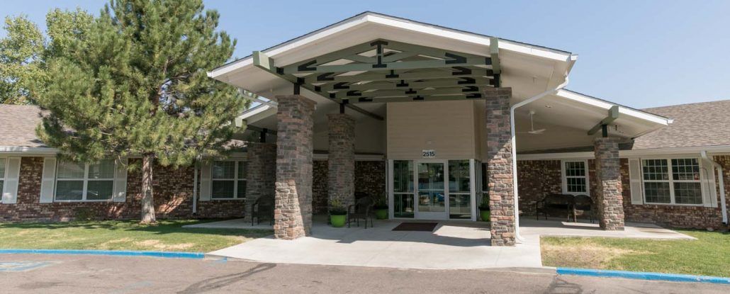 An entrance to a building featuring stone pillars and glass doors, with a large roof overhang.