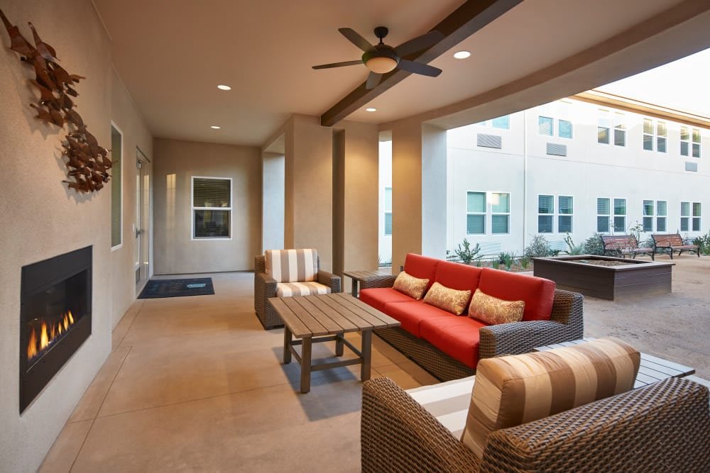 A modern covered patio with comfortable outdoor seating and a ceiling fan.