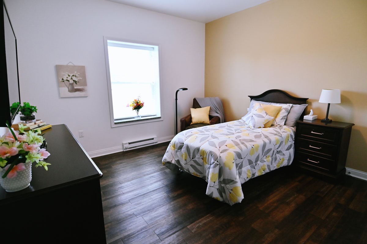A cozy bedroom with modern decor featuring a single bed, wooden floor, and soft lighting.
