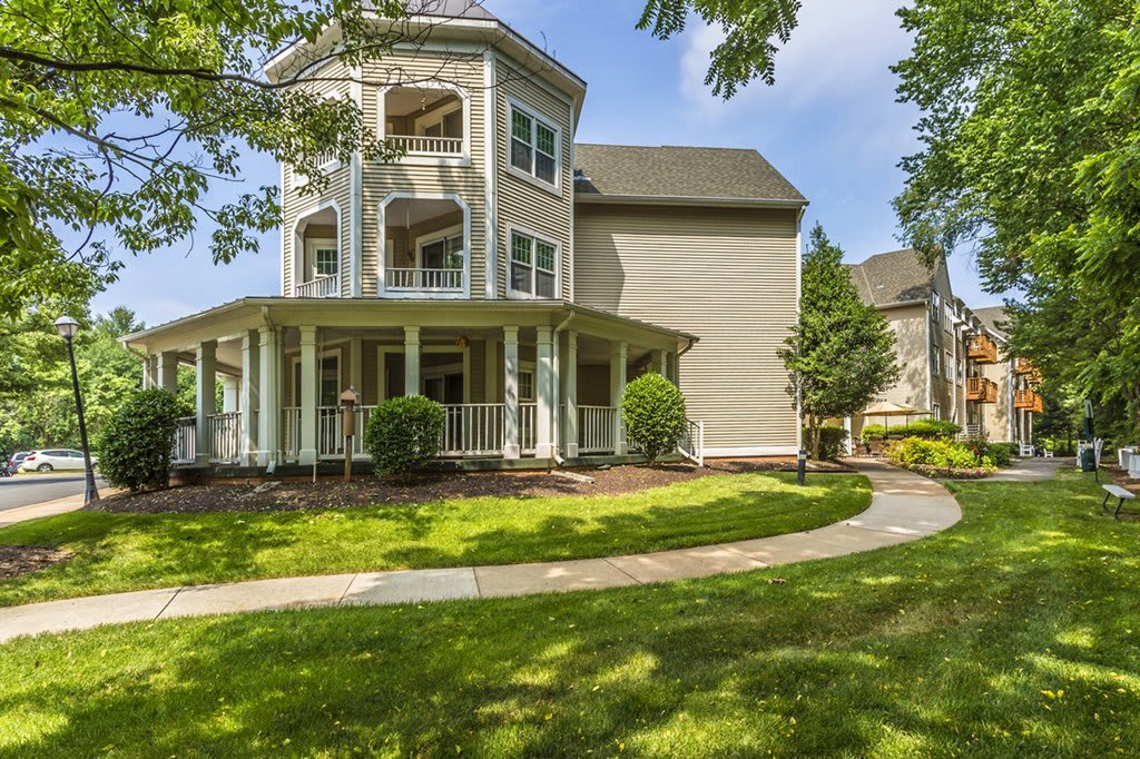 A beautiful two-story house with a wraparound porch and well-maintained lawn.