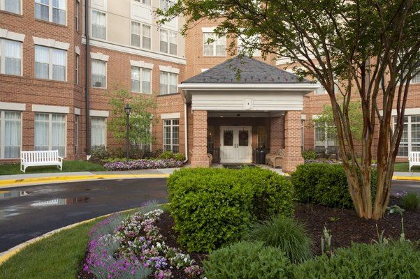 A well-maintained building entrance surrounded by lush landscaping and colorful flowers.