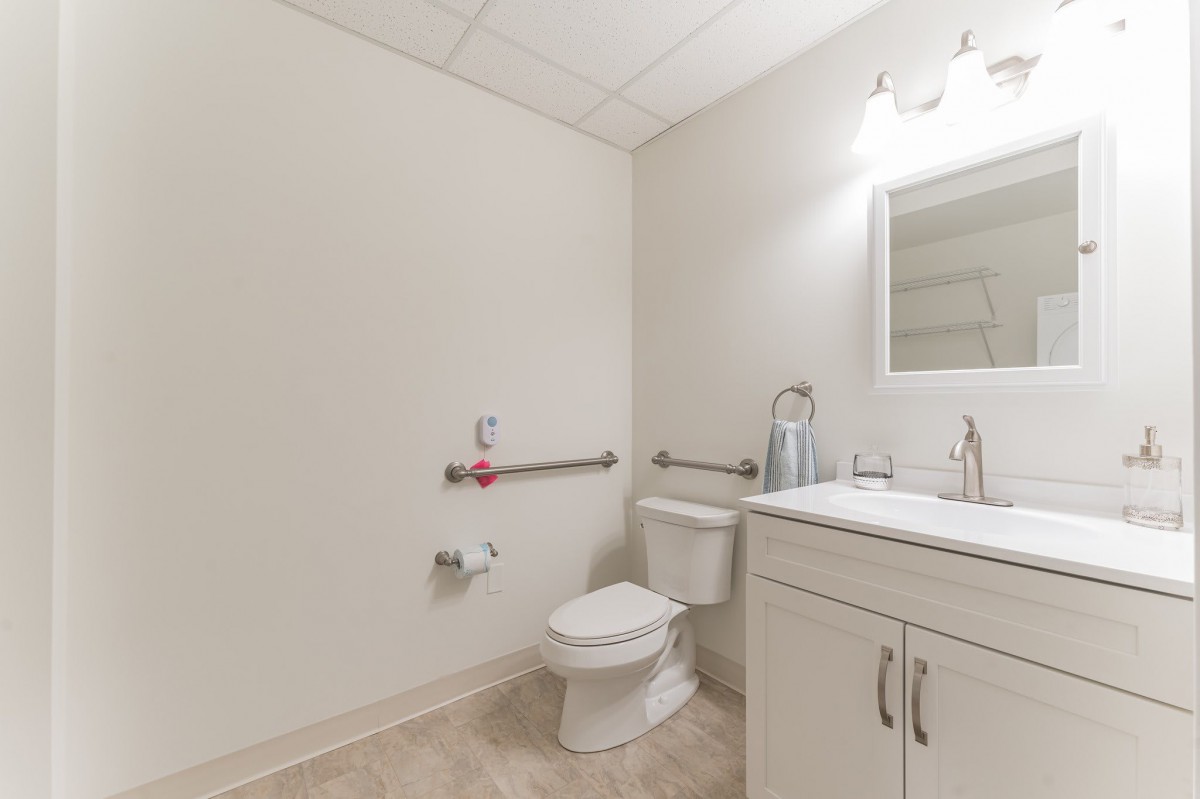 A clean, modern bathroom with a toilet, sink, and mirror.