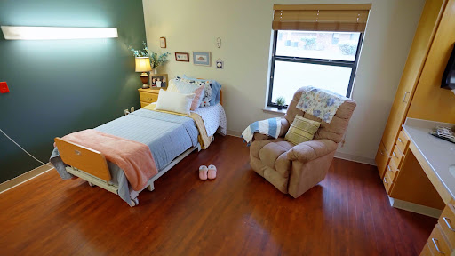 A cozy bedroom setup featuring a neatly made bed, a comfortable armchair, and soft lighting.