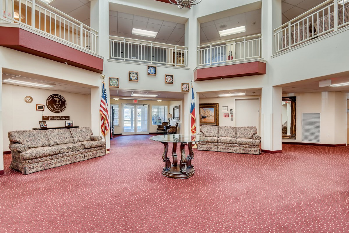 A spacious and elegantly decorated lobby with comfortable seating, flags, and a balcony above.