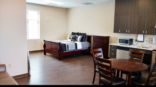 A cozy bedroom setup featuring a comfortable bed, kitchenette, and dining area.