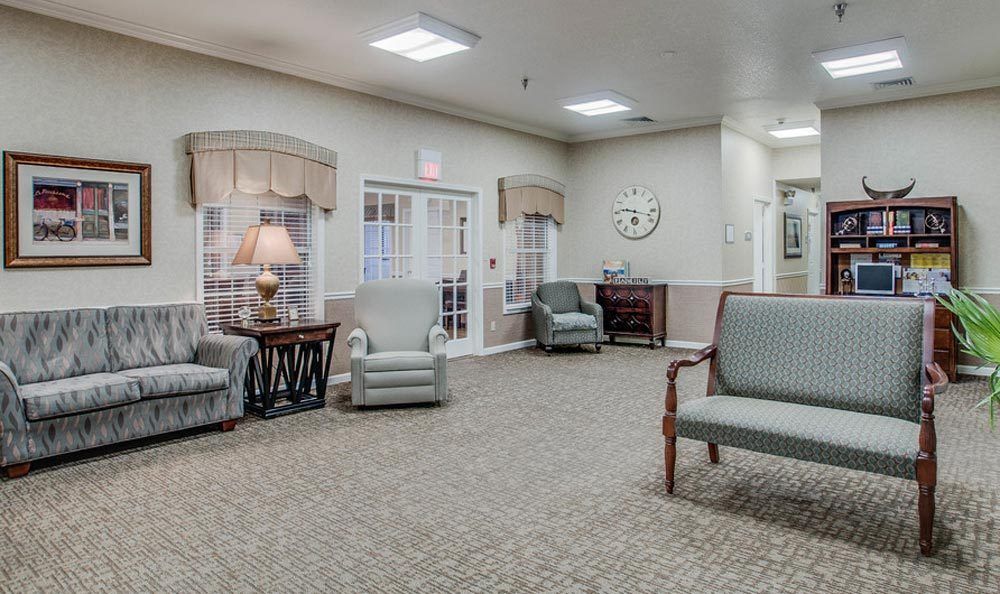 A spacious, well-lit living room area with comfortable seating and a large clock on the wall.