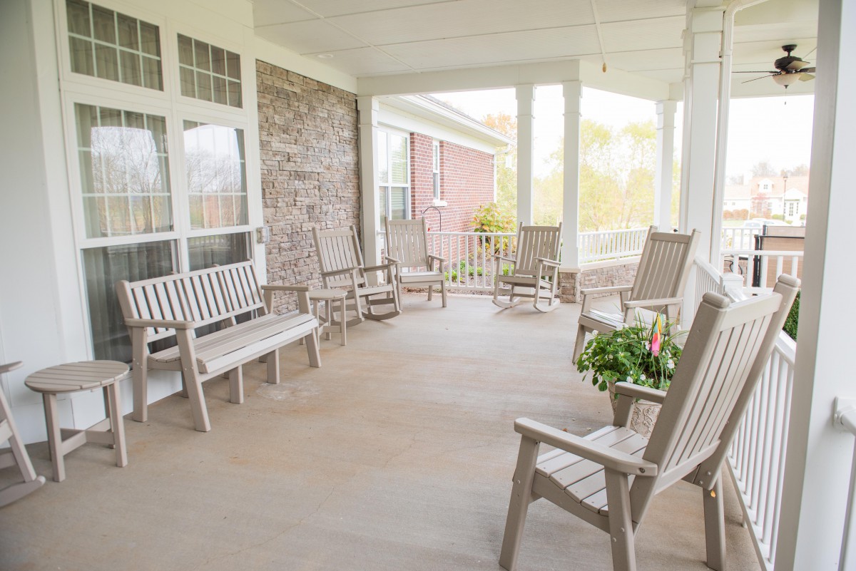 A welcoming porch with wooden rocking chairs and benches, perfect for relaxation.