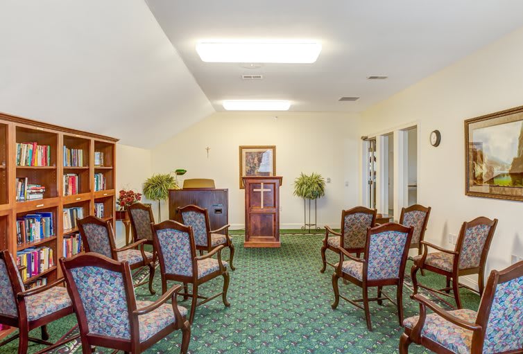 A small chapel room with arranged chairs and a central podium.
