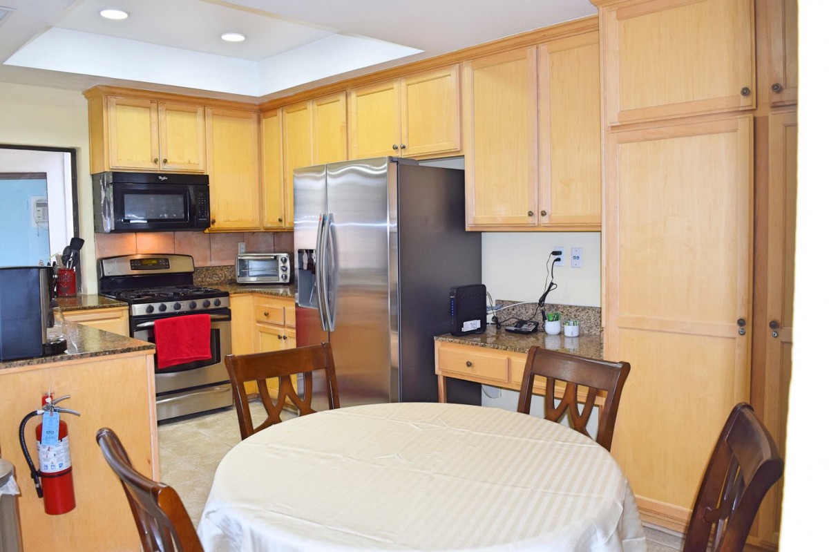 A modern kitchen with wooden cabinets, stainless steel appliances, and a dining table set.