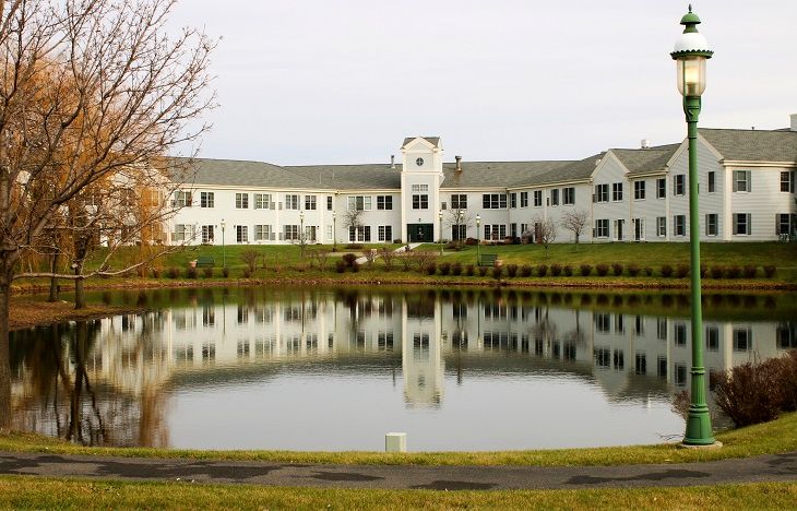 A large building with a pond in the foreground reflecting its image.