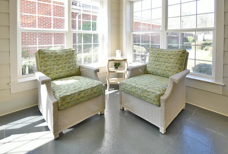 A sunlit room with two cushioned chairs and a small table between them.