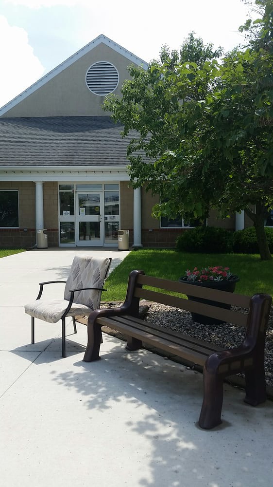 An outdoor seating area with a bench and chair in front of a building entrance.