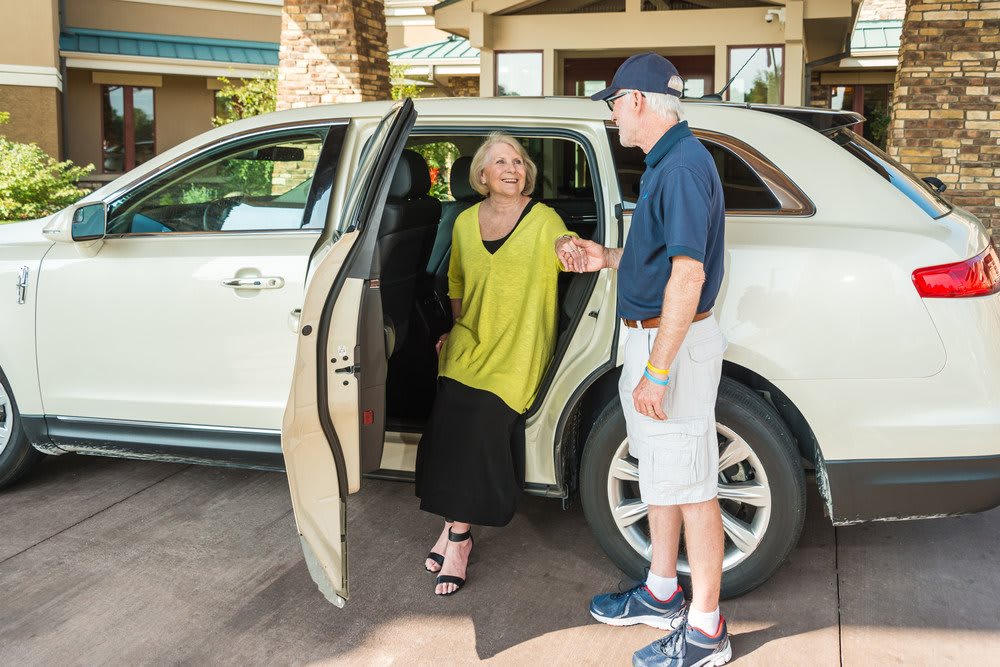 A woman exits a car with the assistance of a valet.