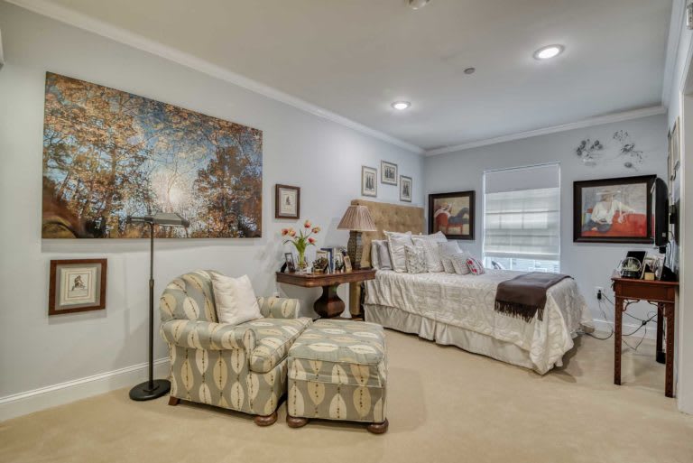 A cozy bedroom with elegant furnishings and artwork on the walls.