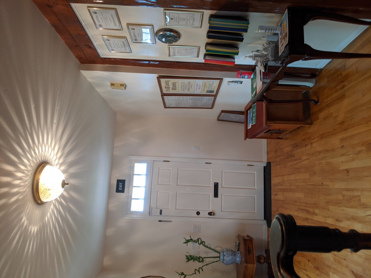 A cozy entryway featuring a white door, hardwood floors, and vintage decor.