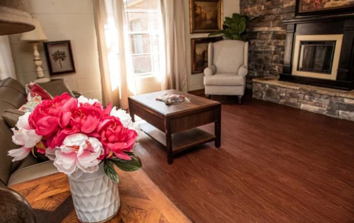 A cozy living room with a coffee table, armchair, and decorative flowers.