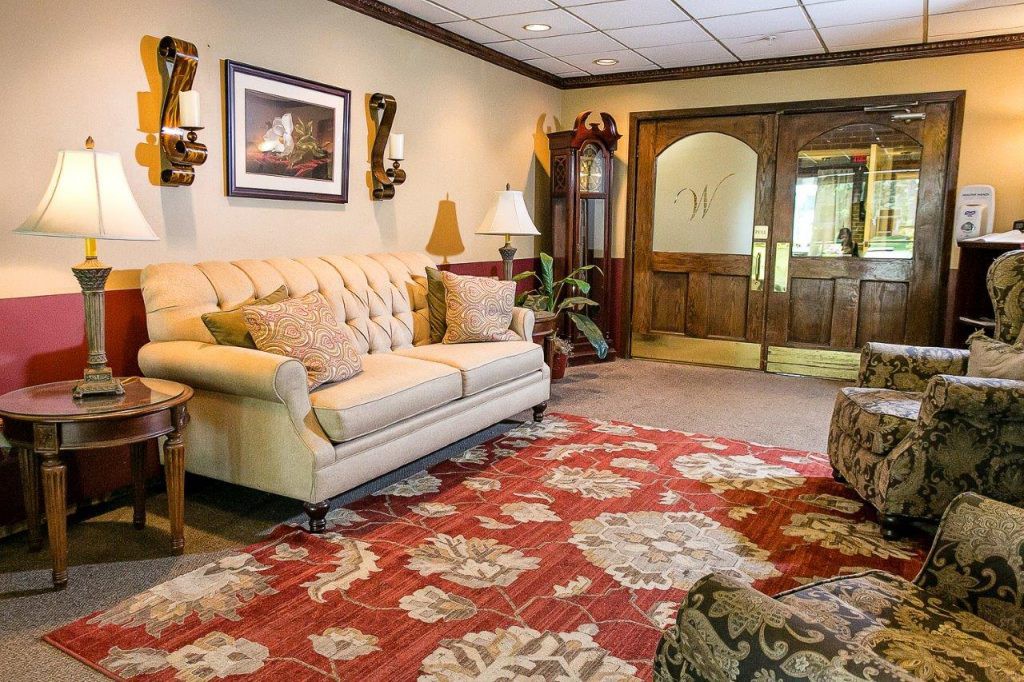 A cozy living room featuring a tufted sofa, ornate rug, and elegant decor with wooden double doors in the background.