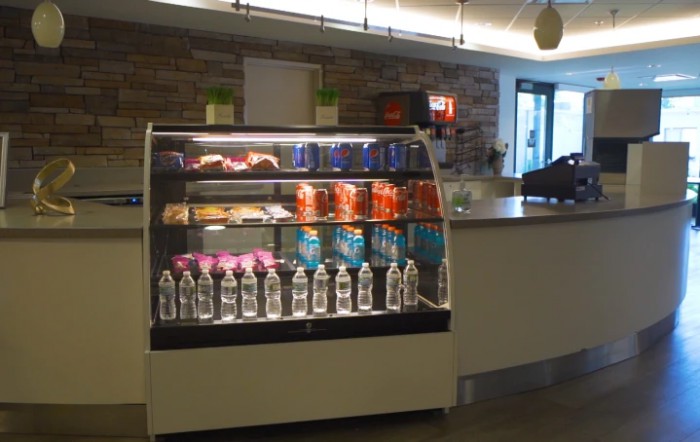A cafe interior featuring a refrigerated display case filled with snacks and bottled water.