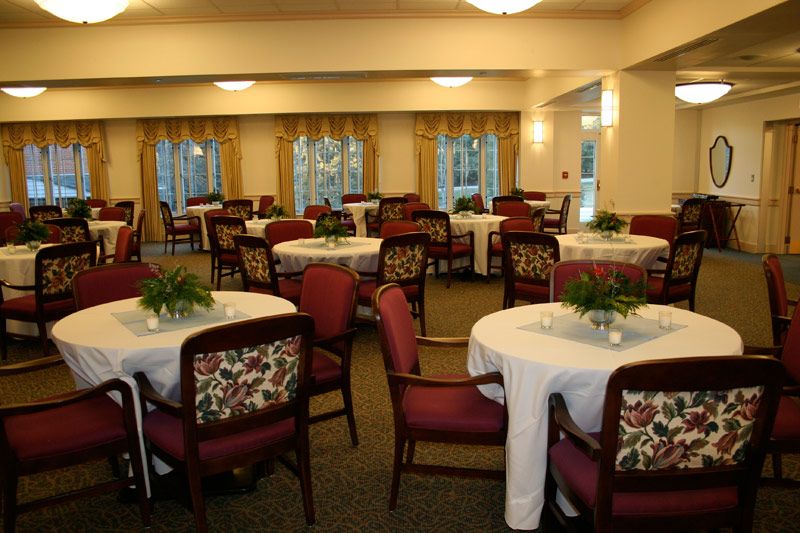 An elegantly arranged dining room with round tables and floral centerpieces.