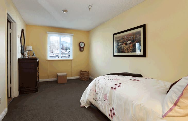 A cozy bedroom with a single bed, wall art, and a window bringing in natural light.